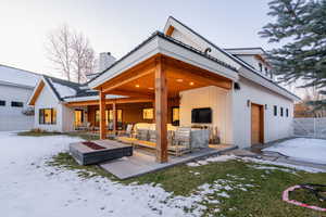 Snow covered rear of property featuring a patio area and an outdoor living space with a fire pit