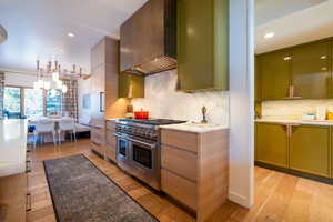 Kitchen featuring custom range hood, light wood-type flooring, double oven range, and green cabinets