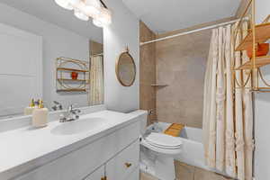 Full bathroom featuring toilet, tile patterned floors, vanity, and shower / tub combo with curtain