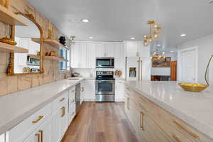 Kitchen featuring sink, white cabinets, stainless steel appliances, and decorative light fixtures