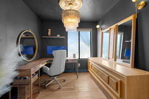 Office with light wood-type flooring and an inviting chandelier