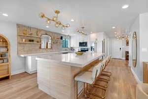 Kitchen featuring a center island, black range with electric cooktop, light hardwood / wood-style floors, high end fridge, and white cabinets