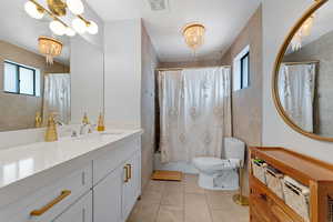 Full bathroom featuring tile patterned floors, vanity, toilet, and a chandelier