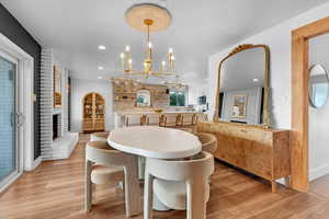 Dining space with a fireplace, light wood-type flooring, and an inviting chandelier