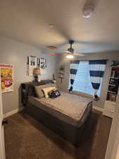 Carpeted bedroom featuring ceiling fan and a textured ceiling