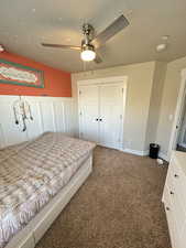 Bedroom with a textured ceiling, a closet, dark carpet, and ceiling fan