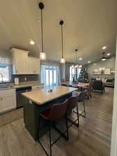 Kitchen featuring white cabinets, sink, dishwasher, a kitchen island, and hanging light fixtures