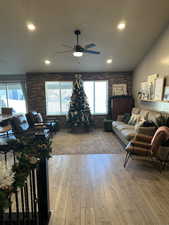 Living room featuring ceiling fan, light hardwood / wood-style floors, and brick wall