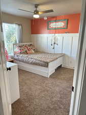 Carpeted bedroom featuring ceiling fan and a textured ceiling