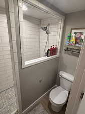 Bathroom featuring a tile shower and toilet