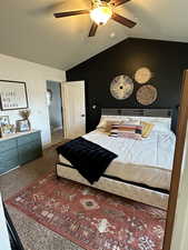 Carpeted bedroom with ceiling fan and vaulted ceiling