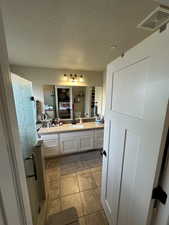 Bathroom with tile patterned flooring, vanity, and a textured ceiling