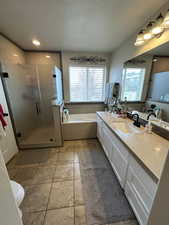 Bathroom with tile patterned floors, vanity, separate shower and tub, and a textured ceiling