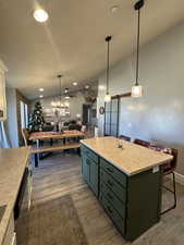 Kitchen with ceiling fan, a barn door, light hardwood / wood-style floors, a kitchen island, and a breakfast bar area