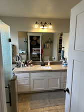 Bathroom featuring tile patterned flooring, vanity, toilet, and a textured ceiling