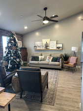 Living room with hardwood / wood-style floors, ceiling fan, and lofted ceiling