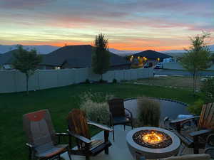 Patio terrace at dusk featuring a lawn, a mountain view, and an outdoor fire pit