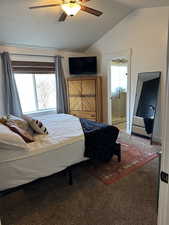 Carpeted bedroom with ceiling fan, lofted ceiling, connected bathroom, and multiple windows