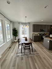 Dining area featuring a textured ceiling, light hardwood / wood-style floors, and a notable chandelier