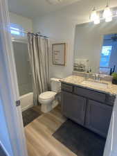 Full bathroom featuring hardwood / wood-style flooring, vanity, a healthy amount of sunlight, and shower / tub combo with curtain