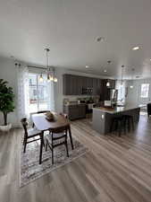 Dining space featuring a textured ceiling, light wood-type flooring, a notable chandelier, and sink