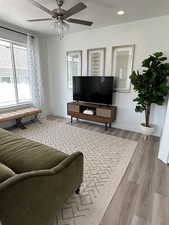 Living room with ceiling fan, light hardwood / wood-style floors, and a textured ceiling