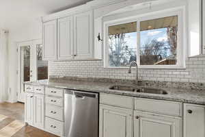 Kitchen with sink, stainless steel dishwasher, plenty of natural light, and light hardwood / wood-style floors