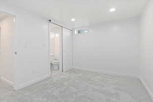 Unfurnished bedroom featuring ensuite bath and light carpet