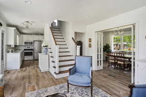 Interior space with white cabinets, appliances with stainless steel finishes, light wood-type flooring, and tasteful backsplash