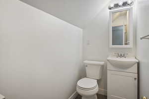 Bathroom with toilet, vanity, and vaulted ceiling