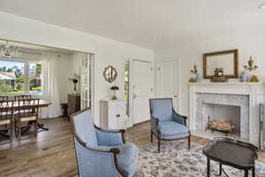 Sitting room with a high end fireplace, a notable chandelier, and hardwood / wood-style flooring