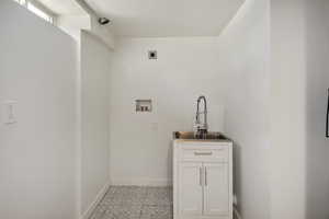 Clothes washing area featuring hookup for an electric dryer, cabinets, sink, and hookup for a washing machine