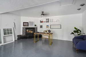 Office featuring a textured ceiling, ceiling fan, and a fireplace