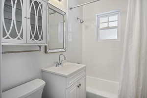 Full bathroom featuring shower / bath combination with curtain, toilet, and vanity