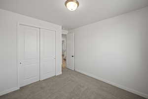 Unfurnished bedroom with light carpet and a closet