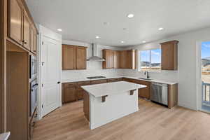 Kitchen with a center island, sink, wall chimney exhaust hood, light hardwood / wood-style floors, and stainless steel appliances