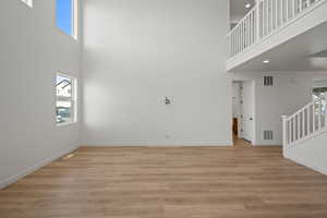 Unfurnished living room featuring a high ceiling and light hardwood / wood-style flooring