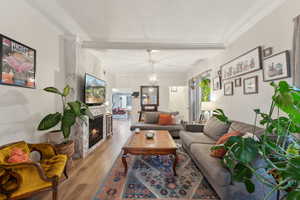 Living room featuring a premium fireplace, crown molding, a textured ceiling, and light wood-type flooring