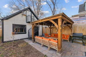 View of patio featuring a gazebo, outdoor lounge area, a grill, and a balcony