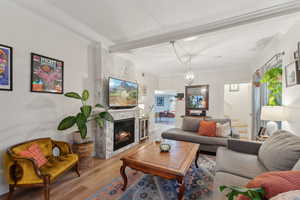 Living room featuring a chandelier, light wood-type flooring, a fireplace, and ornamental molding