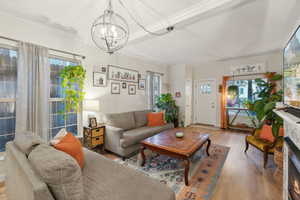 Living room featuring a chandelier, plenty of natural light, ornamental molding, and light wood-type flooring