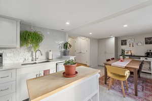 Kitchen featuring tasteful backsplash, dishwasher, sink, and white cabinetry