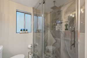 Bathroom with an enclosed shower, plenty of natural light, and toilet