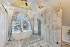 Bathroom featuring ceiling fan, plus walk in shower, and vaulted ceiling