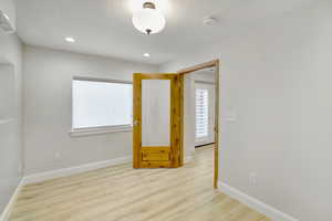 Spare room featuring a textured ceiling and light hardwood / wood-style floors