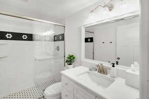 Bathroom featuring walk in shower, vanity, and toilet