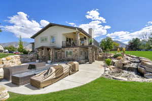 Rear view of house with a balcony, outdoor lounge area, a patio area, a mountain view, and a yard