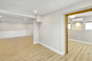 Basement featuring light hardwood / wood-style flooring and a wall mounted AC