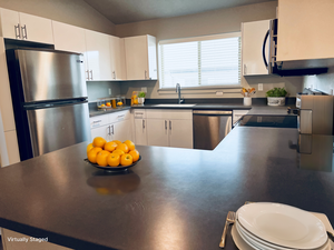 Kitchen featuring sink, white cabinets, vaulted ceiling, and appliances with stainless steel finishes