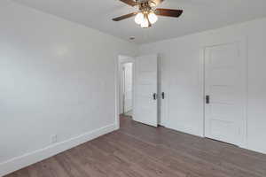 Unfurnished bedroom featuring dark hardwood / wood-style floors and ceiling fan